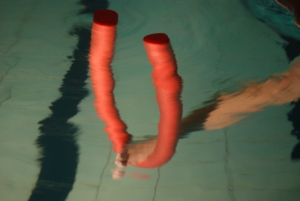 Arm med en rød pølle trener i basseng