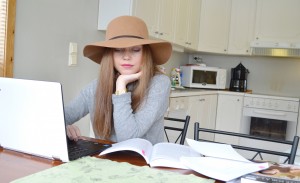 Karoline Brevik sitter ved kjøkkenbordet med bøker og PC