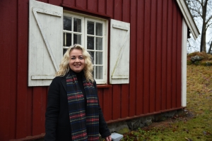 Lillann Wermskog utenfor en rød stue med rutete vinduer