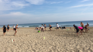 En gjeng som trener ulike øvelser på en sandstrand