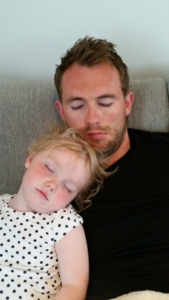 Mann og datter sover sittende på sofaen