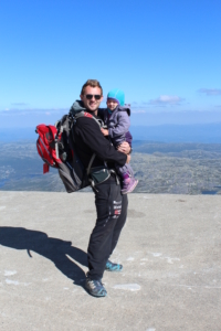 Stian Tollisen med barn i armene på toppen av et fjell