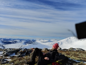Thor-Elvin Jøtulhaug i turklær ligger og ser på utsikt med snødekte fjell