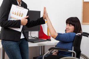 Kvinne i rullestol gir high five til en kollega