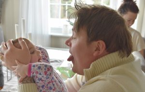 Mann rekker tunge til babyen han holder foran seg