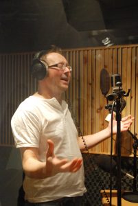 Mann med øretelefoner og mikrofon som joiker i studio
