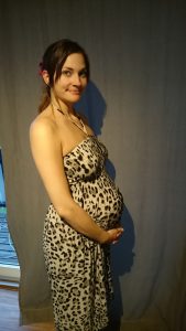Gravid kvinne i kjole holder rundt magen