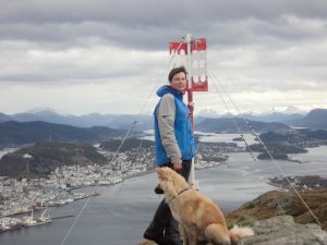 Kvinne og hund på toppen av et fjell med flott utsikt