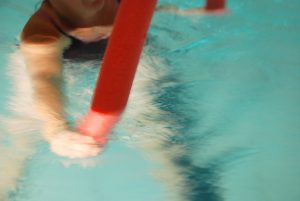 En som padler i vannet med en rød treningspølse