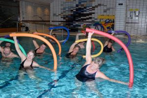 Gruppe mennesker i et basseng trener med fargerike pøller