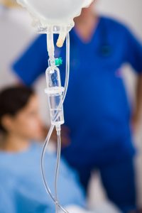 Drypp på sykehus med helsepersonell i blått i bakgrunnen