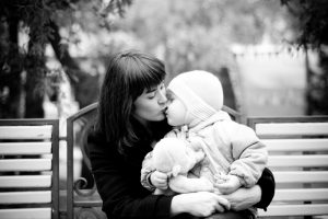 Mor på en benk som kysser sitt barn