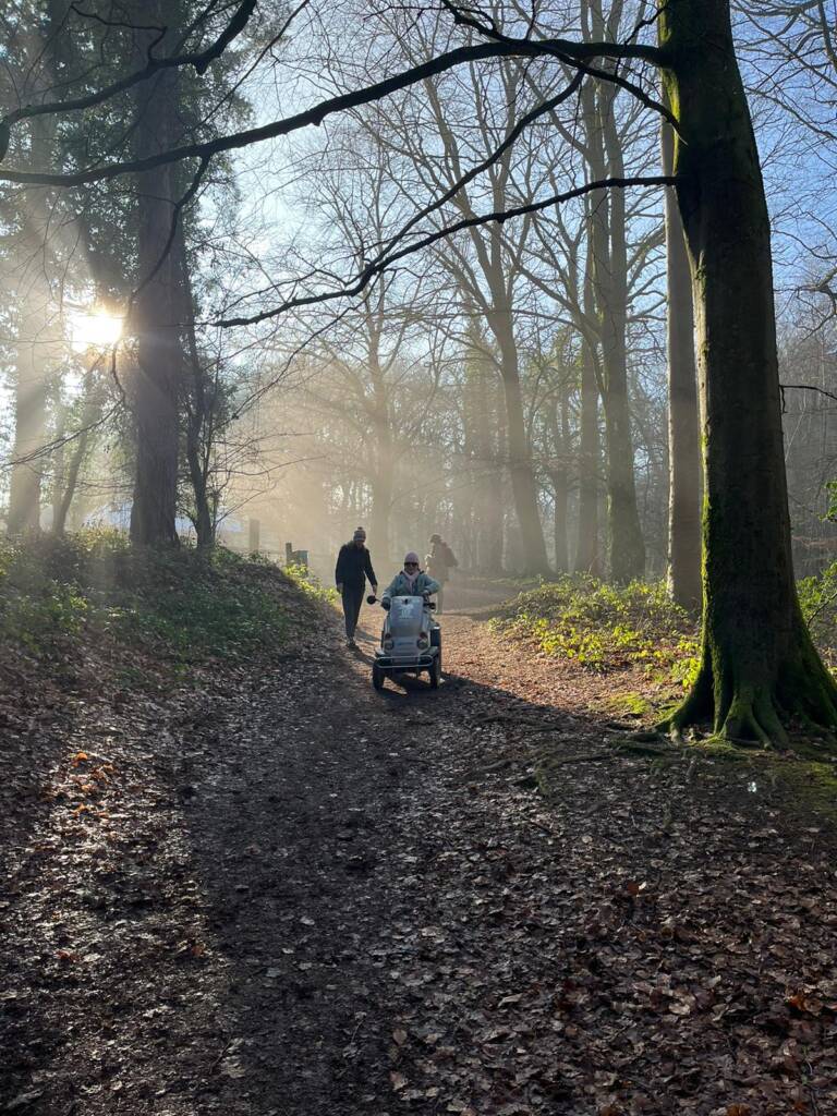 Iddylisk bilde fra høstlig skogstur der Kate kjører elektrisk scooter