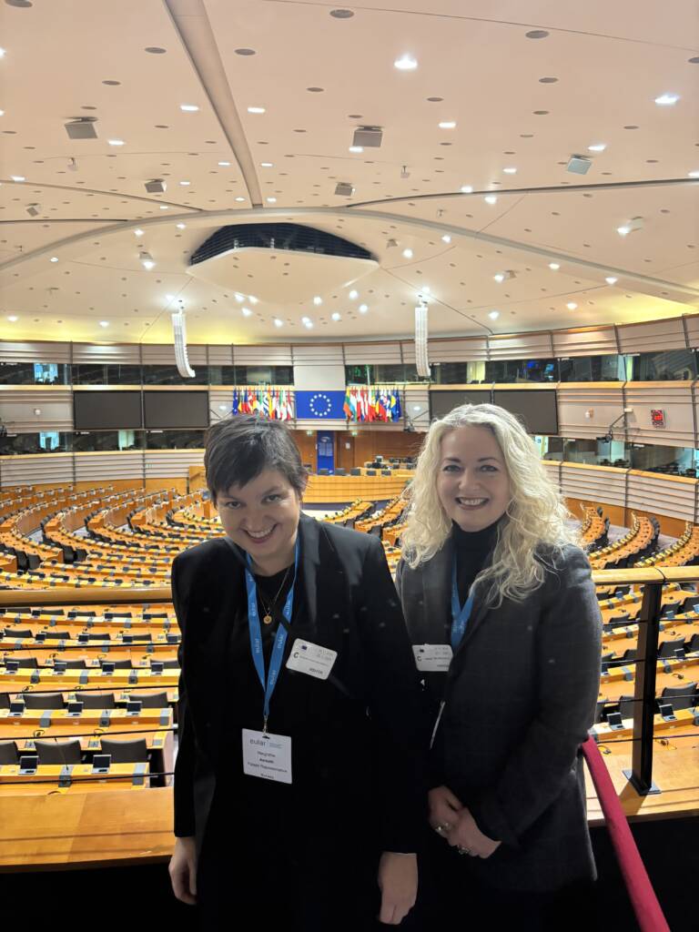 Lillann og Margrethe i hovedsalen i Europaparlamentet omkranset av tolkeboksene